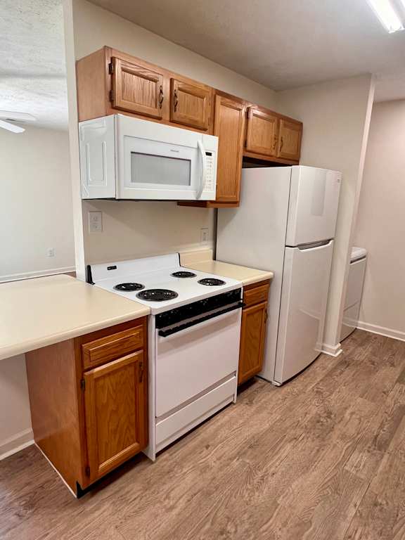 A kitchen with white appliances and wooden cabinets.