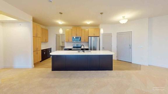 A kitchen with wooden cabinets and a black island.