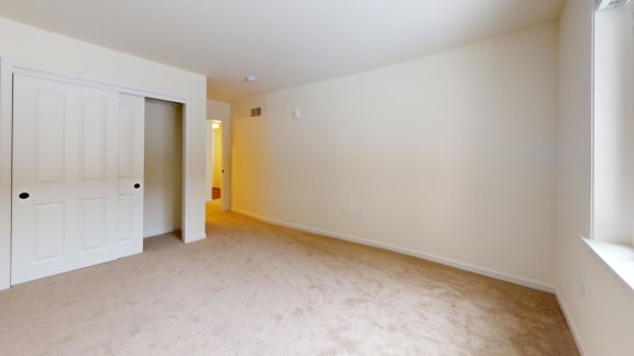 an empty living room with a white door and carpet