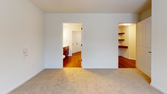 a living room with a carpet and a door to a bedroom