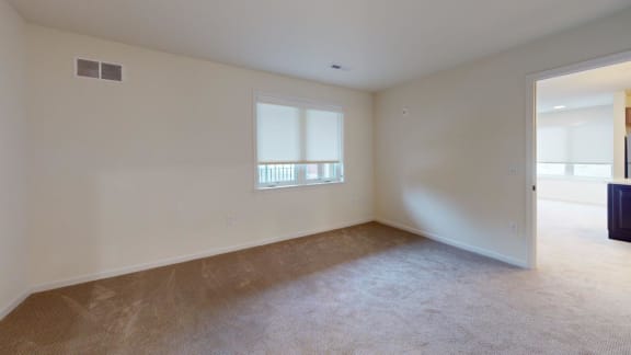 the living room of an empty home with carpet and a window