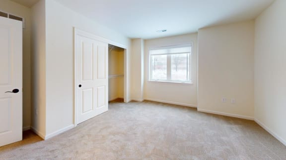 an empty living room with a closet and a window