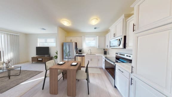 a kitchen and dining room with white cabinets and a table