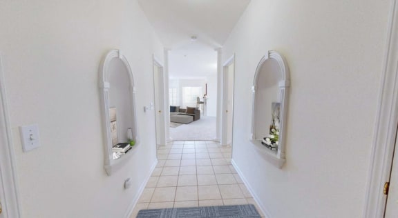 a long white hallway with arched windows and a tiled floor