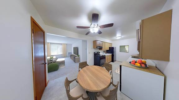 a kitchen and living room with a wooden table and a ceiling fan