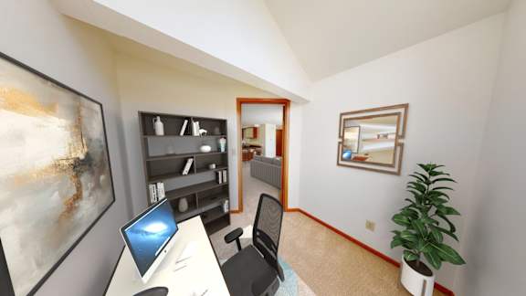 A room with a desk, chair, and a plant.