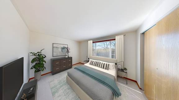 A bedroom with a bed, a plant, and a window.