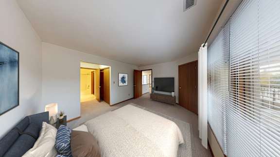A bedroom with a bed, a couch, and a painting on the wall.