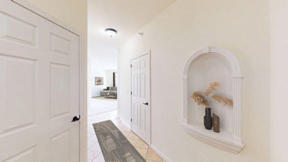 A hallway with a white door and a white wall with a shelf.
