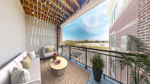 A balcony with a table and chairs overlooking a brick building.