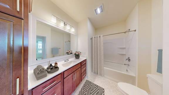 A bathroom with a white tub and a sink with a mirror above it.