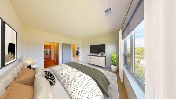 A well-lit bedroom with a large bed and a flat-screen TV.