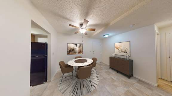 A dining room with a white table and brown chairs.