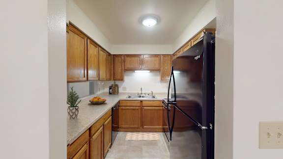 A kitchen with wooden cabinets and a black refrigerator.