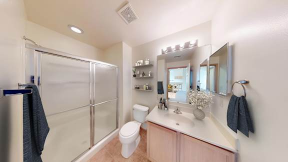 A bathroom with a sink, mirror, toilet, and shower.