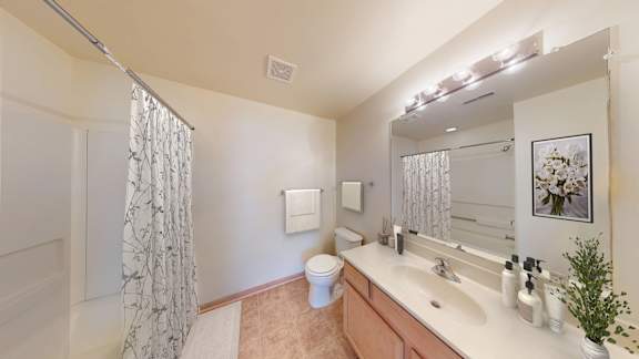 A bathroom with a toilet, sink, and shower curtain.