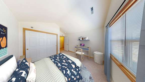 A bedroom with a bed, desk, and chair.