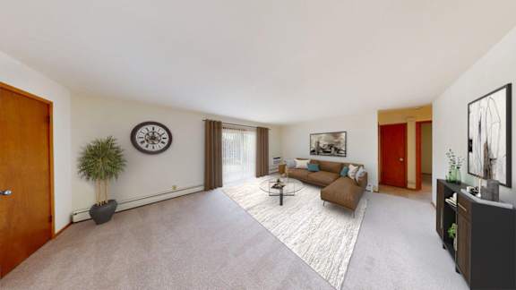 A living room with a brown couch and a large clock on the wall.
