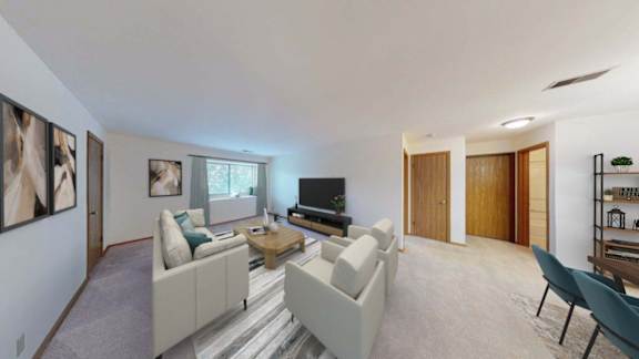 A living room with a white couch, a coffee table, and a television.