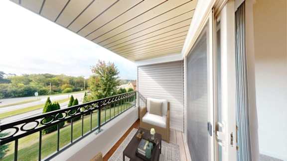 A balcony with a white chair and a table with a bottle on it.