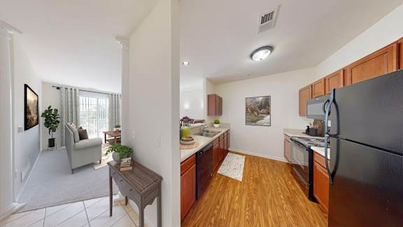 A kitchen with a black fridge and wooden floors.