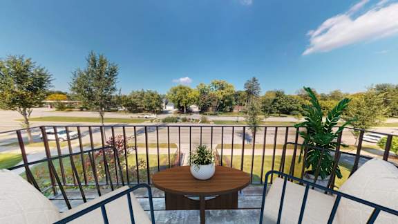 A balcony with a table and chairs overlooking a street.