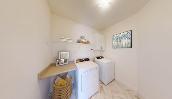 A laundry room with a washer and dryer, a basket, and a picture on the wall.