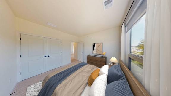 A bedroom with a bed, nightstand, and a window with curtains.
