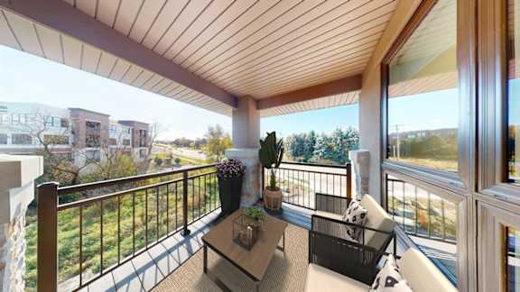 A balcony with a table and chairs overlooking a green area.