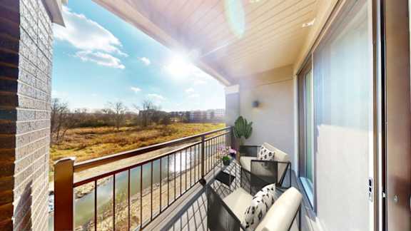 A balcony with a couch and a view of a field.