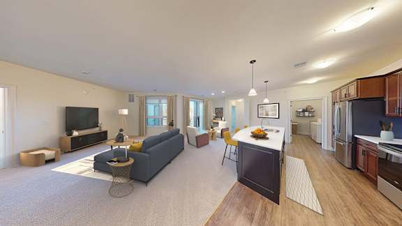 A spacious living room with a grey sofa and a television on a wooden stand.