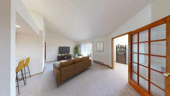 A living room with a brown couch, a television, and a yellow chair.