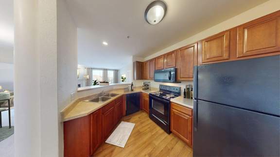 A kitchen with wooden cabinets and a black refrigerator.