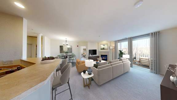 A modern living room with a kitchen area in the background.