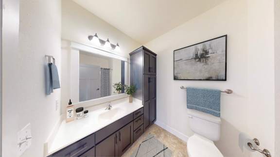A bathroom with a white counter top and a large mirror.