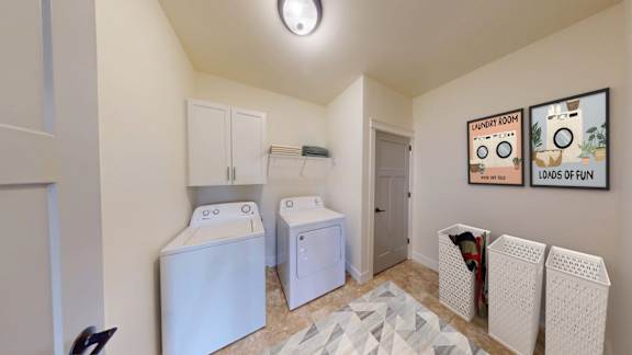 A laundry room with a washer and dryer, a rug, and a picture on the wall.