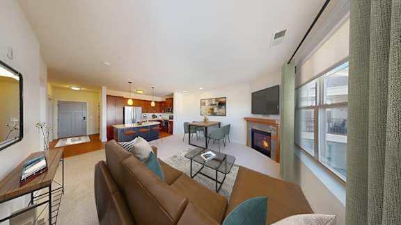 A living room with a brown couch and a fireplace.