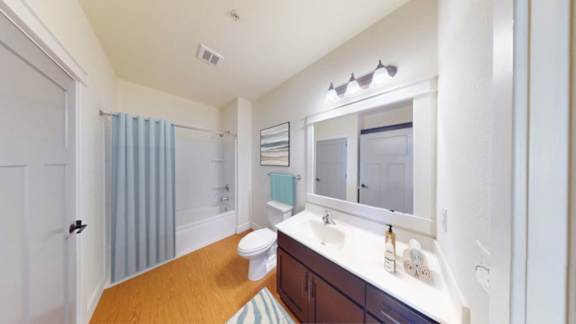 A bathroom with a toilet, sink, and mirror.