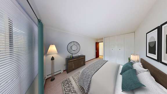 A bedroom with a large bed and a lamp on the side table.