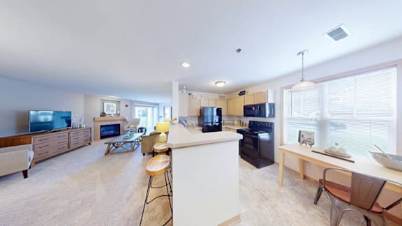 A spacious kitchen and living room with a television, chairs, and a dining table.