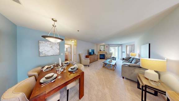 A dining table set with plates and glasses is in the middle of a room with a couch and a television.