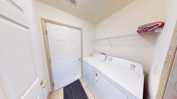 A white door is open to a small laundry room with a washer and dryer.