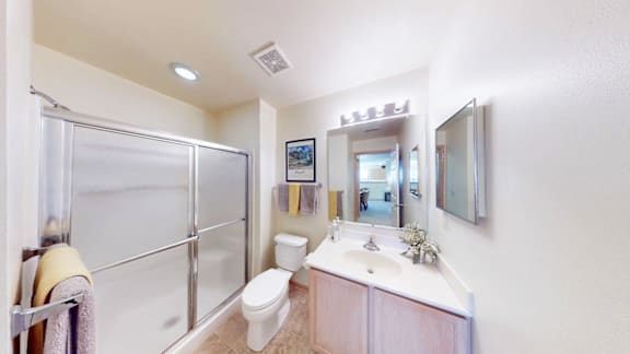 A bathroom with a toilet, sink, mirror, and shower.
