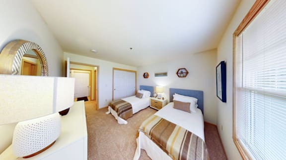 A bedroom with a bed, a chair, and a mirror.