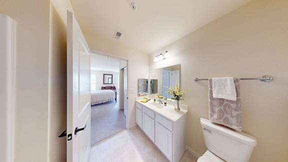A white bathroom with a toilet, sink, and mirror.
