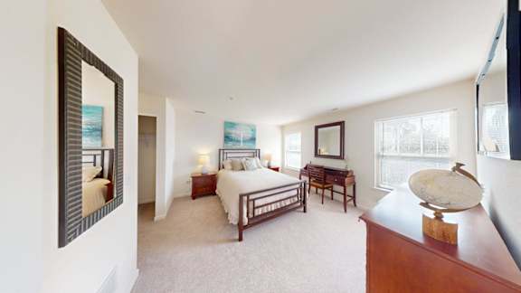 A bedroom with a bed, desk, and chair.