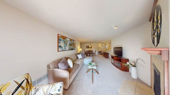 A living room with a couch, chairs, and a painting on the wall.