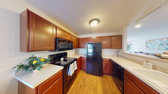 A kitchen with wooden cabinets and a black refrigerator.
