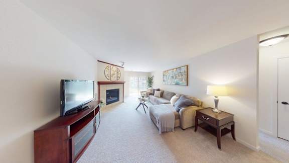 A living room with a television, a couch, a bed, and a fireplace.