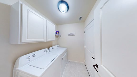 A white washing machine is in a small laundry room.